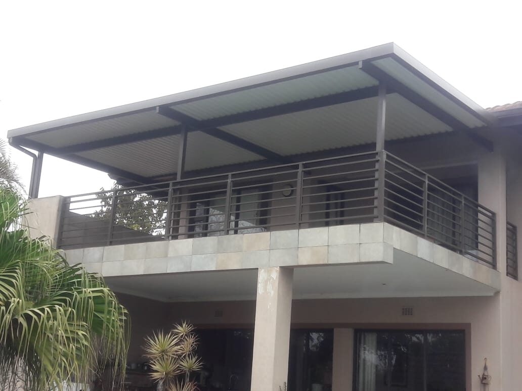 Charcoal-framed flat-roof patio cover shading a first-floor balcony