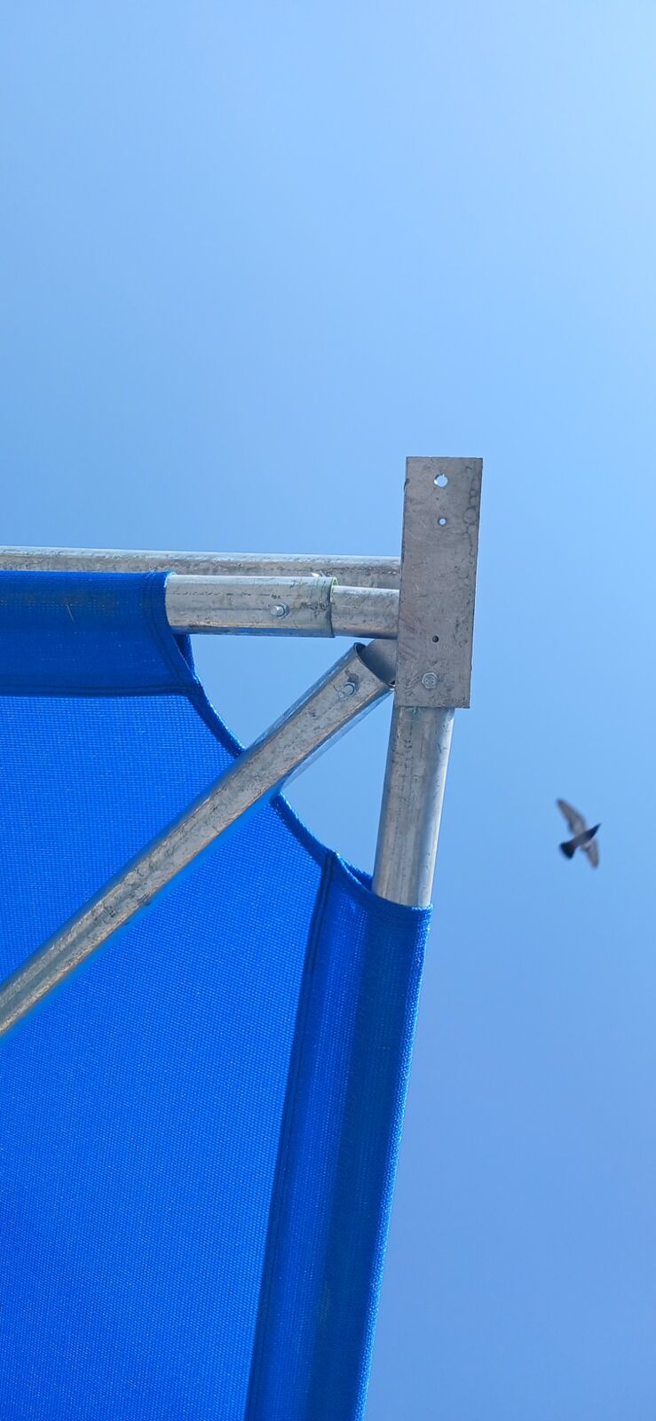 Blue shade cloth stretched and clamped to the galvanised corner bracket of a shadeport frame